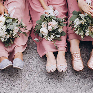 bridesmaids in pink dresses are sitting and holding bouquets of